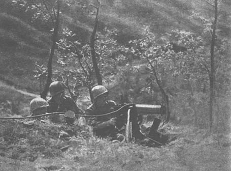 [A machine gun crew fires against the Germans dug in on Monticelli]