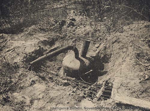 [A fougasse flame-thrower emplacement, partly uncovered, showing the control wires leading to a central switchboard.]