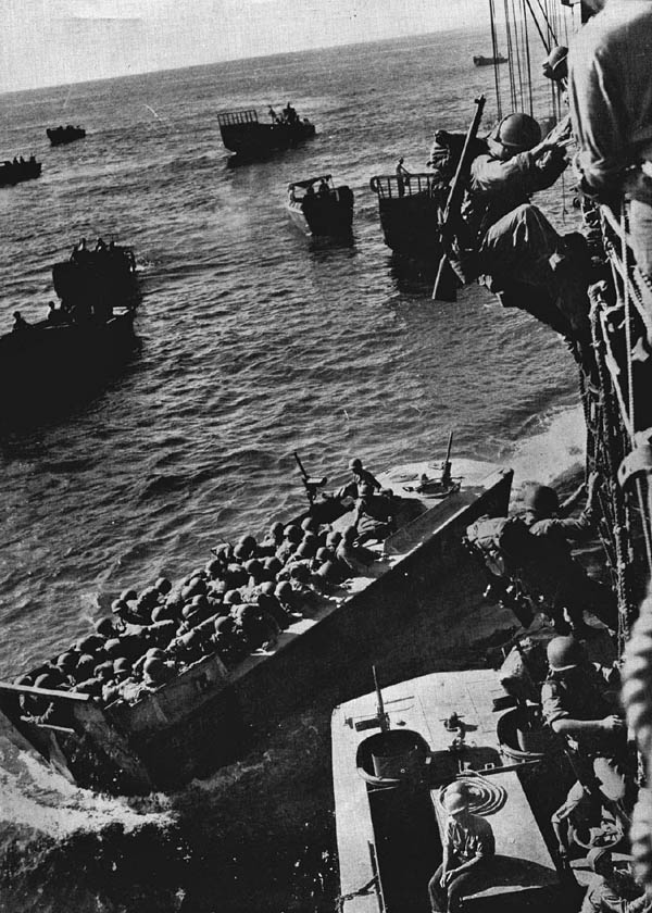 U.S. troops go over the side of a Coast Guard-manned combat transport to enter landing craft for the invasion of Empress Augusta Bay, Bougainville.  (Official U.S. Coast Guard Photograph.)