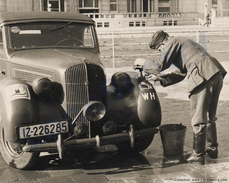 A German soldier in Westende, Belgium washes a civilian car impressed into German military service.