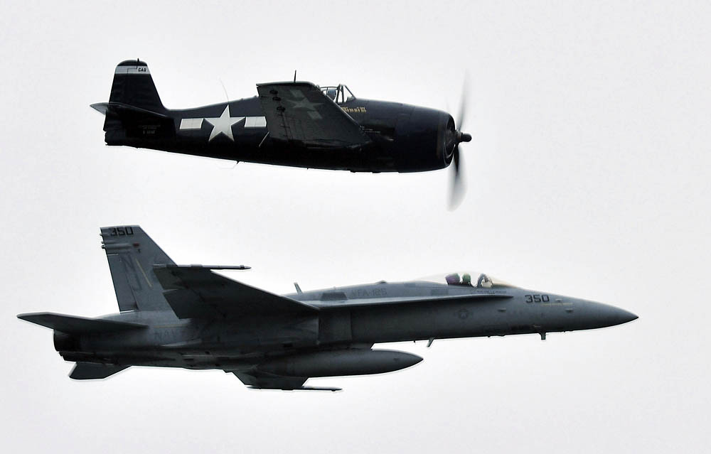 F6F Hellcat flies alongside an F/A-18C Hornet assigned to the Rough Raiders of Strike Fighter Squadron 125