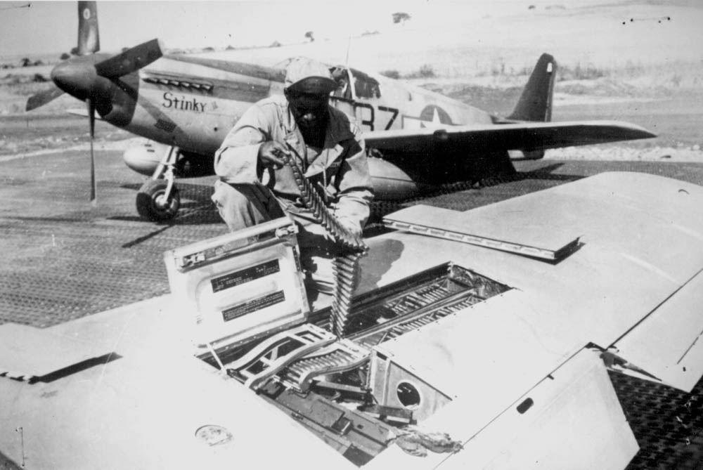 An armorer of the 15th U.S. Air Force checks ammunition belts of the .50 caliber machine guns in the wings of a P-51 Mustang fighter plane before it leaves an Italian base for a mission against German military targets.
