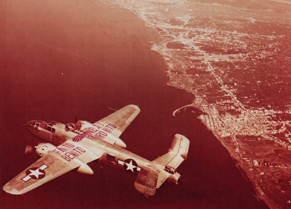 A 12th BG North American B-25 Mitchell bomber with "Finito Benito, Next Hirohito" wing markings flying over the Gulf of Naples. (U.S. Air Force Photograph.)