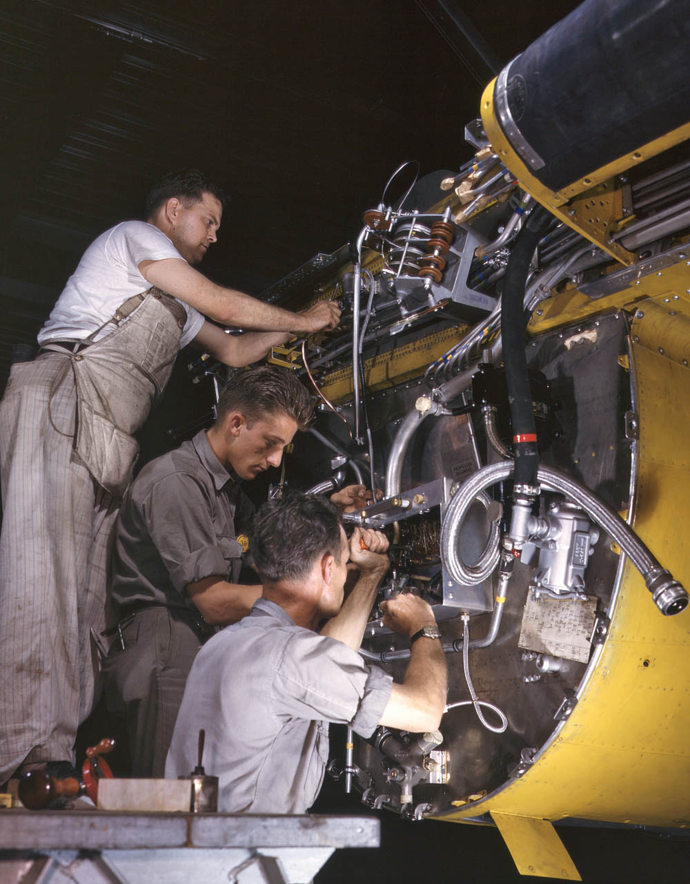 Factory workers wire the right engine of a B-25 bomber under assembly at North American Aviation in Inglewood, California, June 1942. (Alfred T. Palmer / U.S. Library of Congress.)