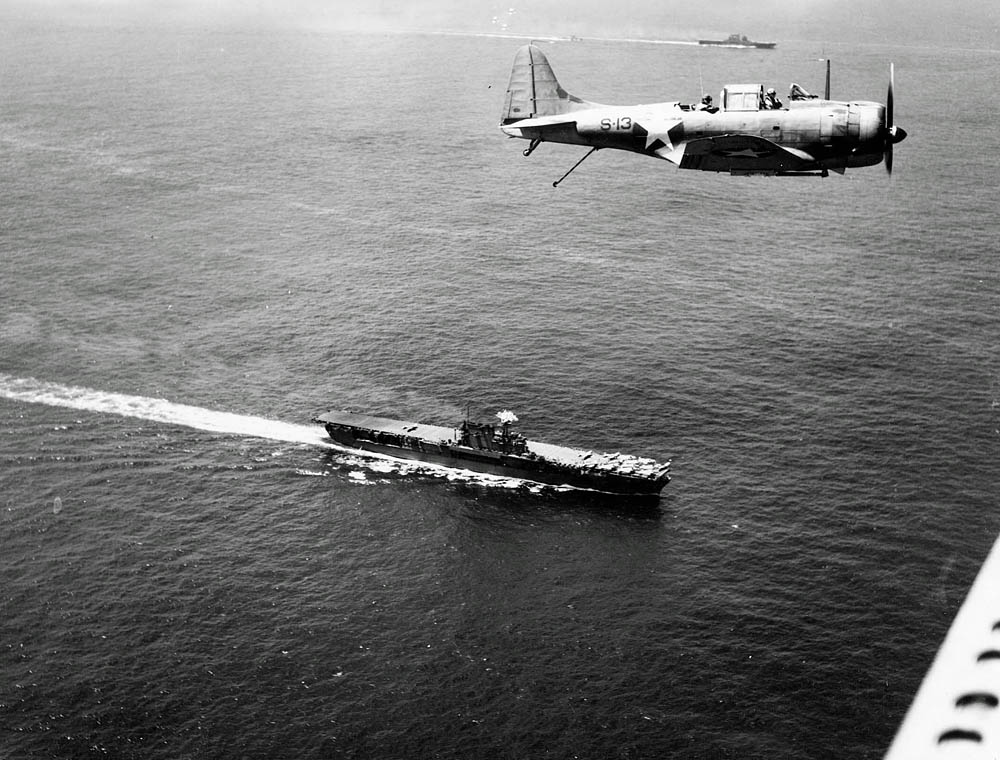 A Douglas SBD-3 Dauntless flies over the USS Enterprise (CV-6) and USS Saratoga (CV-3) near Guadalcanal in December 1942.