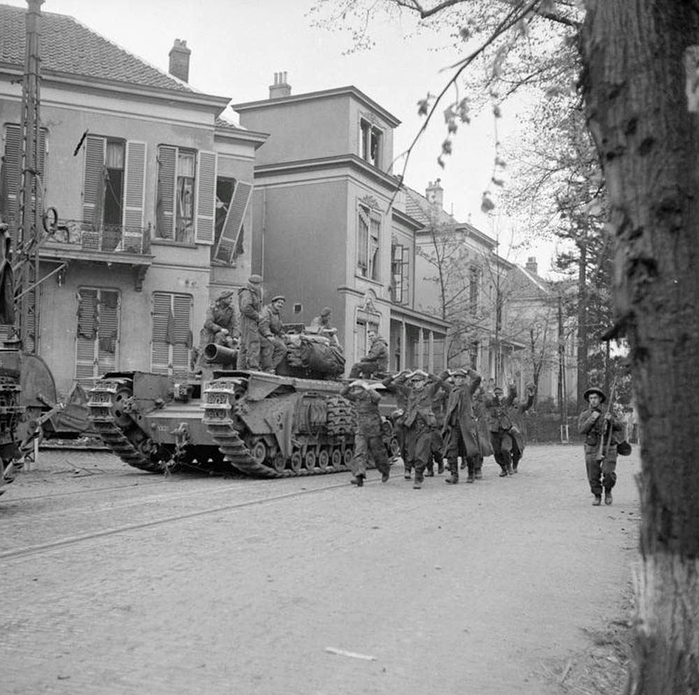 Captured German prisoners are marched by a Churchill AVRE tank in Arnhem during Operation Anger in April 1945. (Collections of the Imperial War Museums.)
