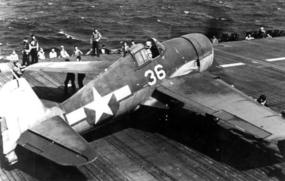 Sailors on the USS Hornet fold the wings of a Grumman F6F Hellcat fighter after a raid over the Marianas, June 1944.