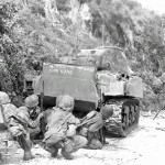 U.S. Marines of 2nd Marine Division take cover behind "King Kong," an M4 Sherman tank, on the northern end of Saipan.