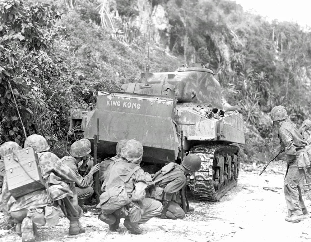 U.S. Marines of 2nd Marine Division take cover behind "King Kong," an M4 Sherman tank, on the northern end of Saipan.