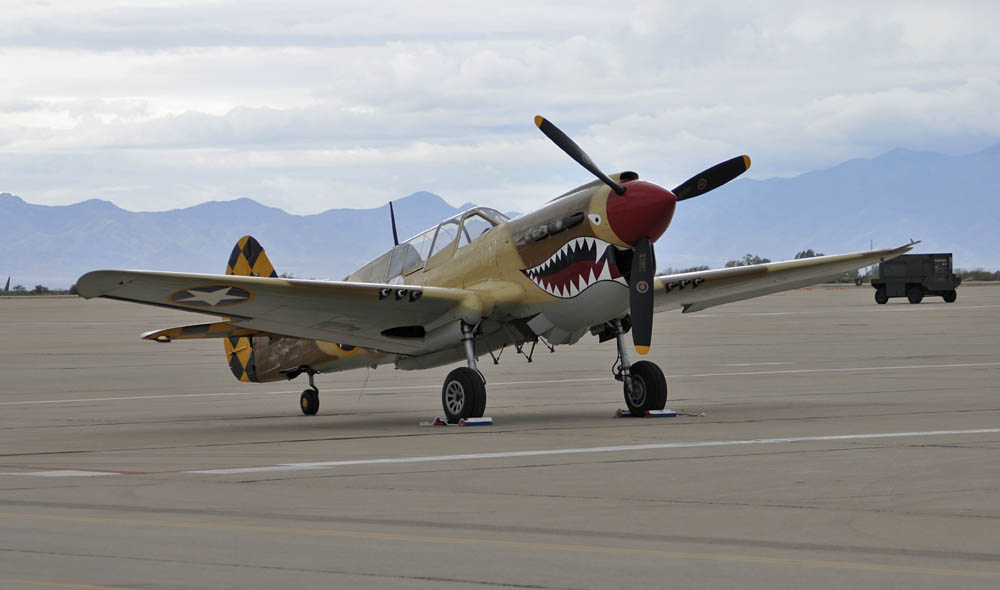A P-40N Warhawk Air Force Heritage aircraft on the flight line at Davis-Monthan Air Force Base, Ariz., during the Heritage Flight Training Course (HFTC) March 1, 2014. Additional aircraft participating in the HFTC were the P-51 Mustang, the P-38 Lightning, the P-47 Thunderbolt and the F-86 Sabre. Air Combat Command aircraft include the F-22 Raptor, A-10 Thunderbolt II and the F-16C Fighting Falcon.