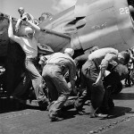 Sailors from the USS Lexington move an aircraft with a flat tire down the flight deck, November 1943. (U.S. National Archives Photograph.)