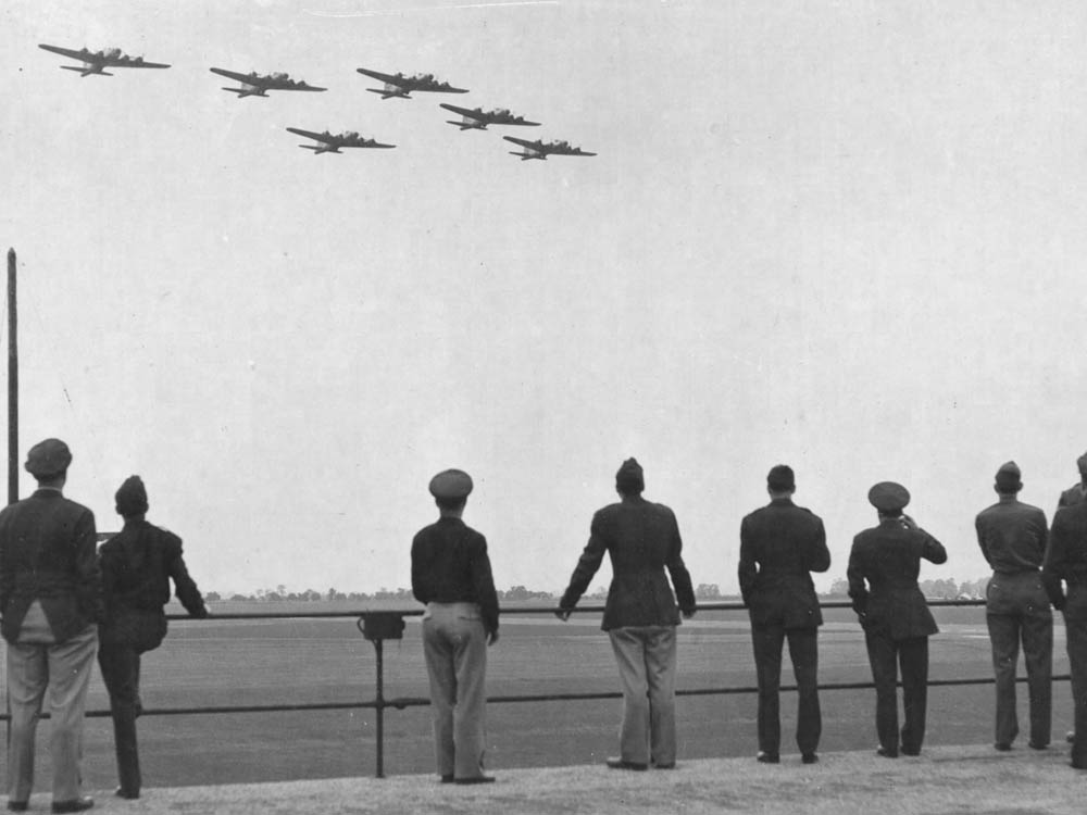 Soldiers from the 379th BG watch a formation of Boeing B-17 Flying Fortresses return to base after a mission in June 1944. (U.S. Air Force Photograph.)