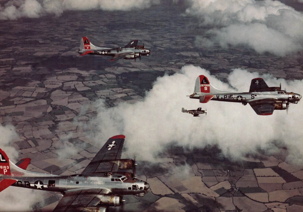 A lone P-51 Mustang fighter flies with a formation of B-17 Flying Fortress bombers over England. (U.S. Air Force Photograph.)