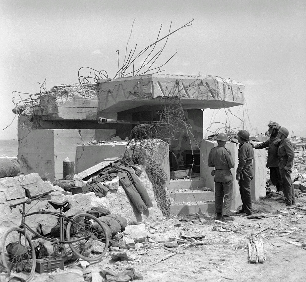 Allied troops examines a knocked-out German bunker on Gold Beach, June 1944. (Imperial War Museum Photograph.)