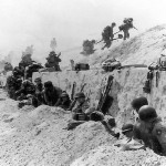 Soldiers from the 8th Infantry Regiment, 4th Infantry Division prepare to advance over the seawall on Utah Beach during the D-Day invasion. (U.S. Navy Photograph.)