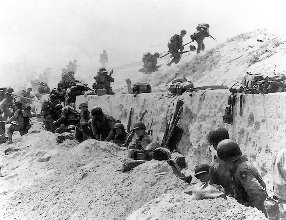 Soldiers from the 8th Infantry Regiment, 4th Infantry Division prepare to advance over the seawall on Utah Beach during the D-Day invasion. (U.S. Navy Photograph.)