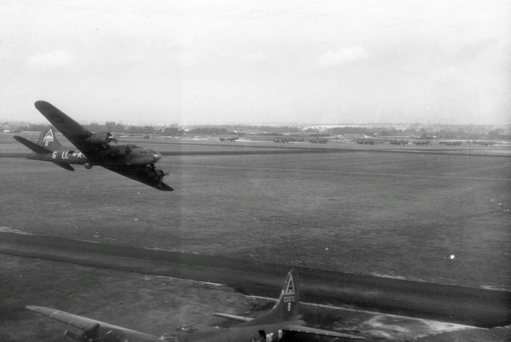 A Boeing B-17F Flying Fortress of the 401st Bomb Squadron makes a low level pass over a second parked B-17 of the 324th Bomb Squadron at Bassingbourn, England. (U.S. Air Force Photograph.)