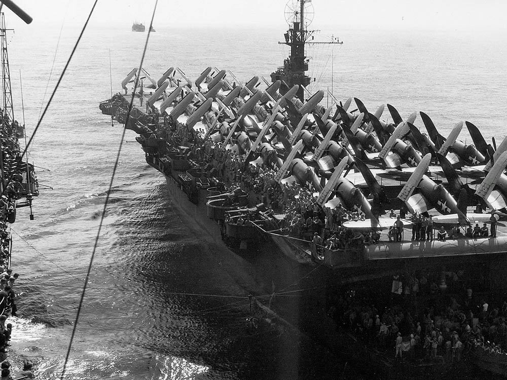 The escort carrier USS Attu (CVE-102), loaded with Vought F4U Corsairs on the flight deck, photographed alongside the Clemson-class destroyer USS Fox, September 1945.
