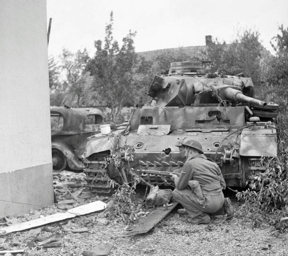 A British soldier takes cover in front of a knocked-out German Panzer III in Oosterhout near Nijmegen, September 1944. (Imperial War Museum Photograph.)