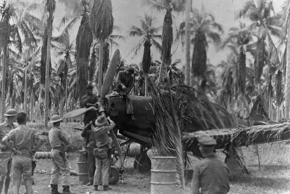 A Bell P-39 Airacobra camouflaged with palm fronds is serviced on an island in the Pacific. (U.S. Air Force Photograph.)
