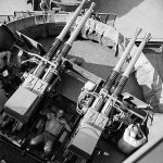 Sailors sleep at their quad 40mm gun position on the USS New Jersey (BB-62). (National Archives Photograph.)