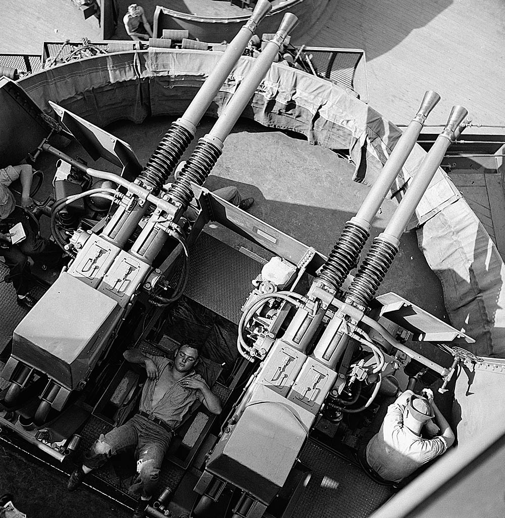 Sailors sleep at their quad 40mm gun position on the USS New Jersey (BB-62). (National Archives Photograph.)