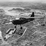 A U.S. Marine observation plane flies over Naha, Okinawa. (U.S. National Archives Photograph.)