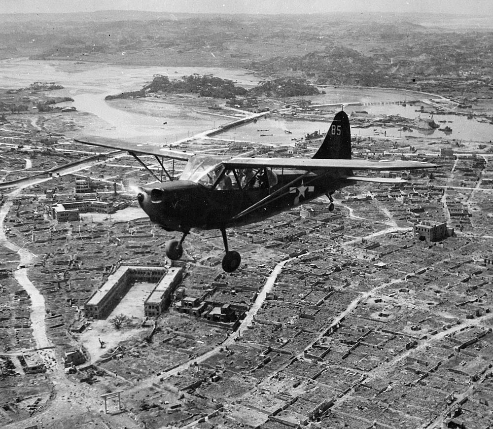 A U.S. Marine observation plane flies over Naha, Okinawa. (U.S. National Archives Photograph.)
