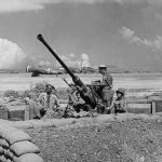 A gun crew from the 864th Antiaircraft Battery mans a 40mm antiaircraft gun at Isley Field on Saipan, Mariana Islands in July 1944. Thunderbolts and Avengers are visible in the background. (U.S. Air Force Photograph.)