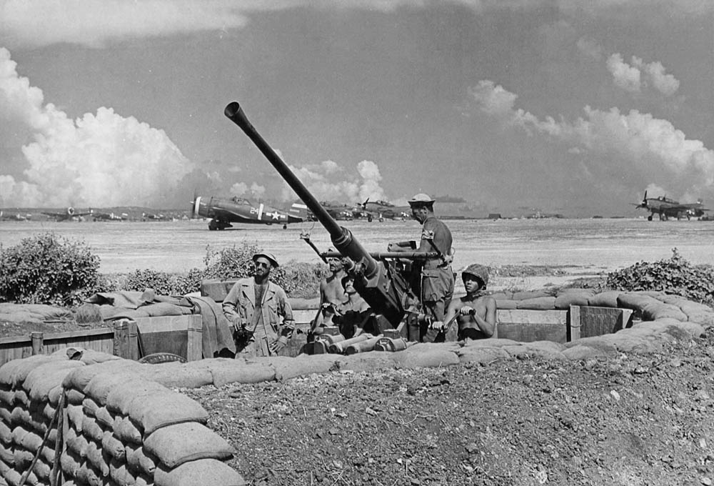 A gun crew from the 864th Antiaircraft Battery mans a 40mm antiaircraft gun at Isley Field on Saipan, Mariana Islands in July 1944. Thunderbolts and Avengers are visible in the background. (U.S. Air Force Photograph.)