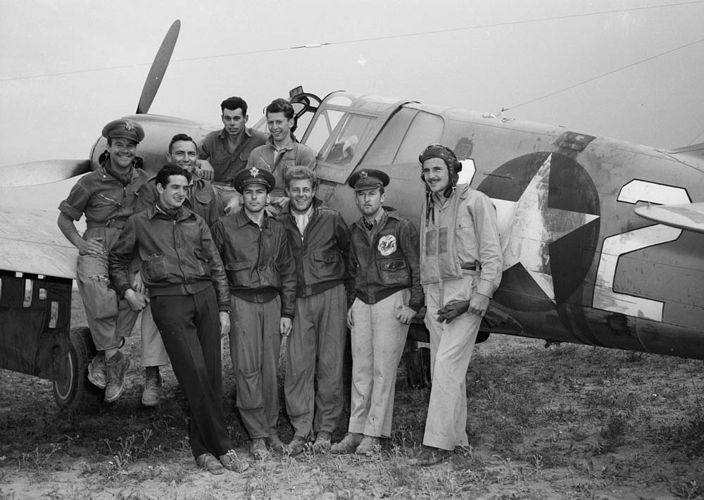 Pilots and airmen from the 64th Fighter Squadron of the 57th Fighter Group pose for a photograph in front of a unit fighter. (Library of Congress Photograph.)