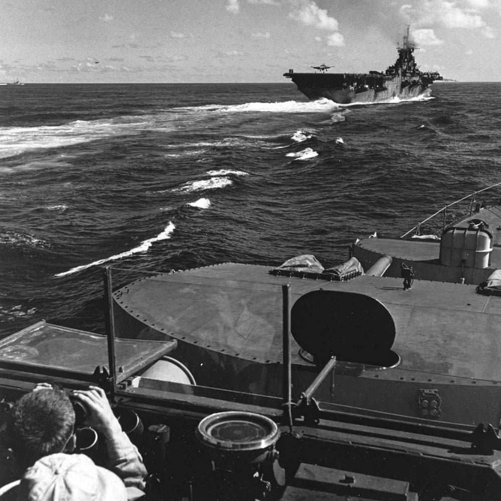Sailors on the destroyer USS Ault (DD-698) watch a Grumman F6F-5 Hellcat from Fighting Squadron 87 (VF-87) land on the aircraft carrier USS Ticonderoga (CV-14) in July 1945. (U.S. Navy Photograph.)