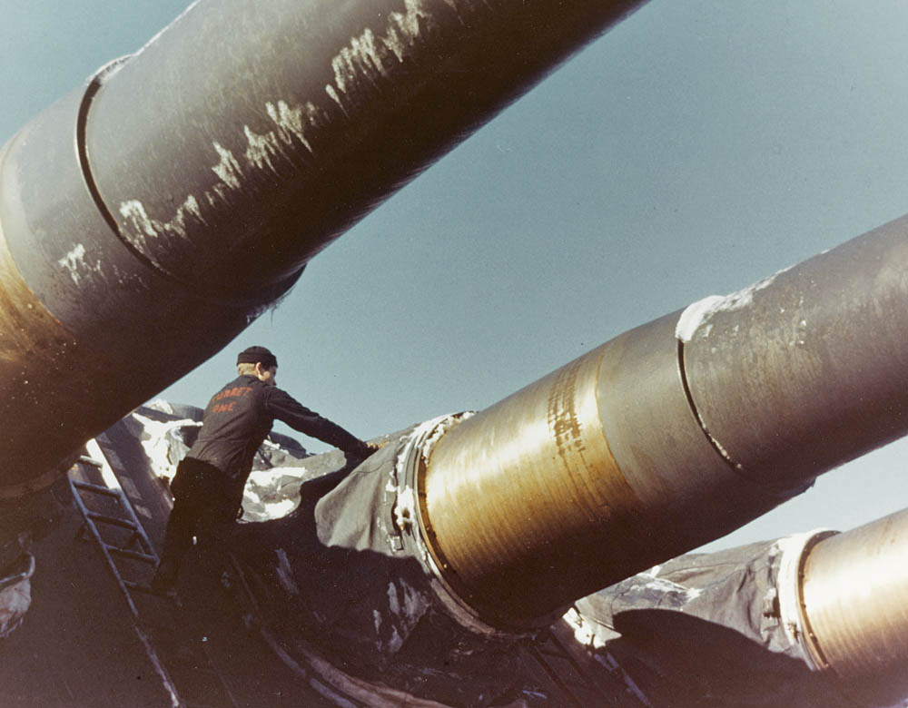 A sailor on the battleship USS Alabama cleans ice and snow off the battleship's 16-inch guns during the ship's North Atlantic shakedown cruise, December 1942 to January 1943. (U.S. Navy Photograph.)