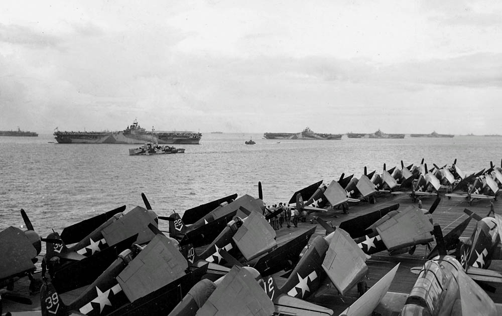 Hellcats and Avengers on the flight deck of the carrier USS Ticonderoga (CV-14) are shown in the foreground of the U.S. Navy aircraft carriers USS Wasp (CV-18), USS Yorktown (CV-10), USS Hornet (CV-12), and USS Hancock (CV-19) anchored in Ulithi Atoll. (U.S. Navy Photograph.)