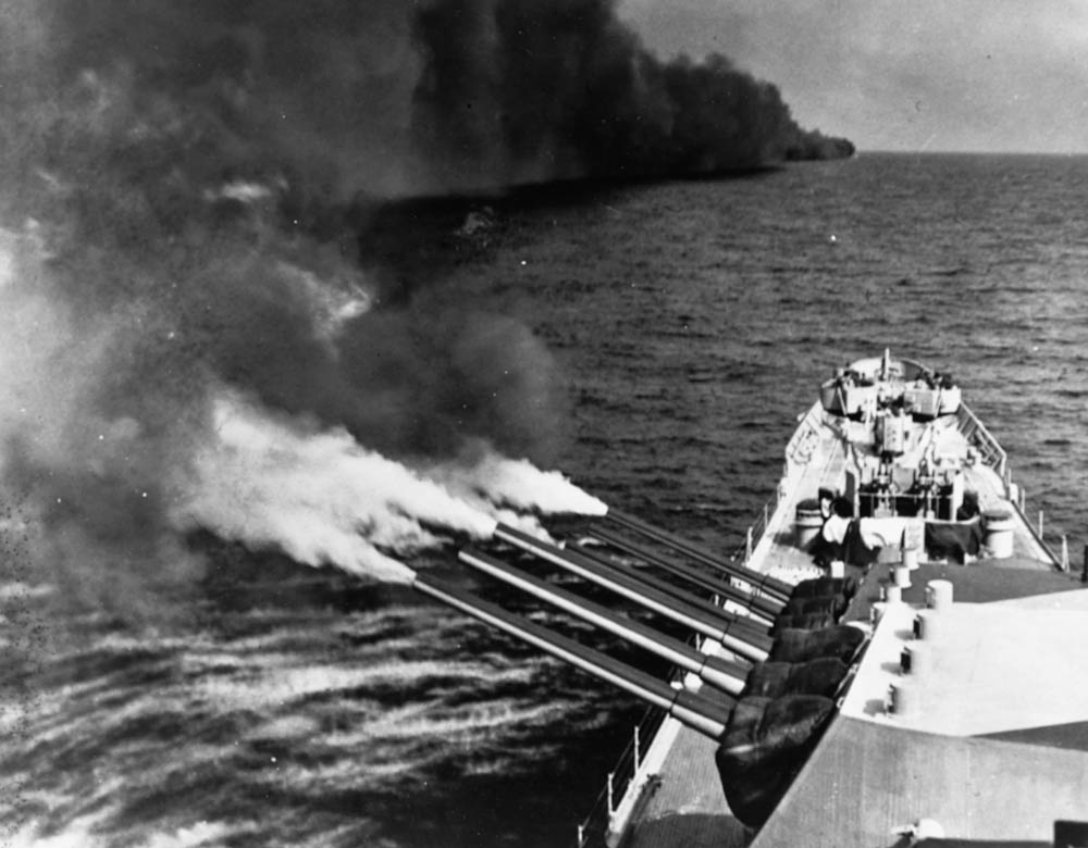 In August 1944, the USS Quincy (CA-71) Baltimore-class heavy cruiser fires her forward 8-inch guns at German positions. A smoke screen laid by another ship is visible in the background. (U.S. Navy Photograph, National Archives and Records Administration.)