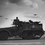 A halftrack on guard duty watches as a flight of Republic P-47 Thunderbolts of the 318th Fighter Group return to their airfield in the Okinawa Islands after a strike on Japan. (U.S. Air Force Photo)