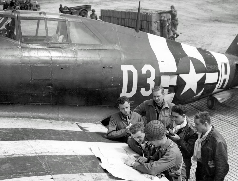 Pilots of U.S. 9th Air Force consult maps on the wing of a P-47 Thunderbolt fighter-bomber near St. Mere Eglise, France in June 1944. (U.S. Air Force Photograph.)