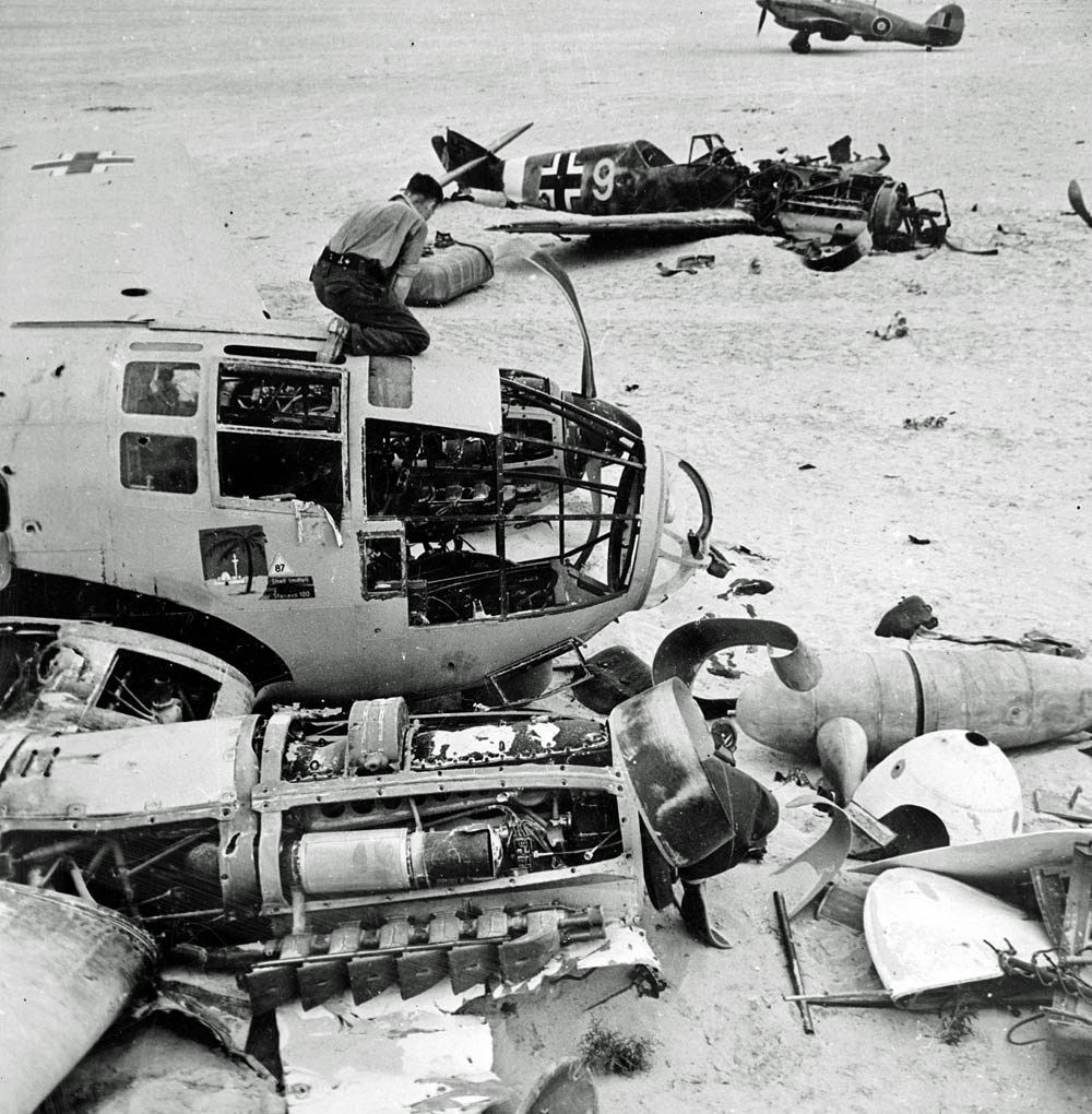 Allied troops inspect a wrecked German Heinkel He 111 bomber and Messerschmitt Bf 109 fighter on a landing field in Egypt, 1942.