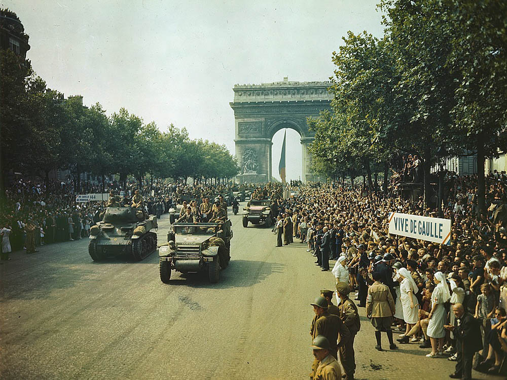 Allied tanks and halftracks pass through the Arc de Triomphe and parade down the Champs-Élysées after the liberation of Paris.