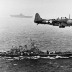 U.S. Navy Douglas SBD-5 Dauntless flies over the battleship USS Washington (BB-56) during the invasion of the Gilbert Islands, November 1943. (U.S. Navy Photograph.)