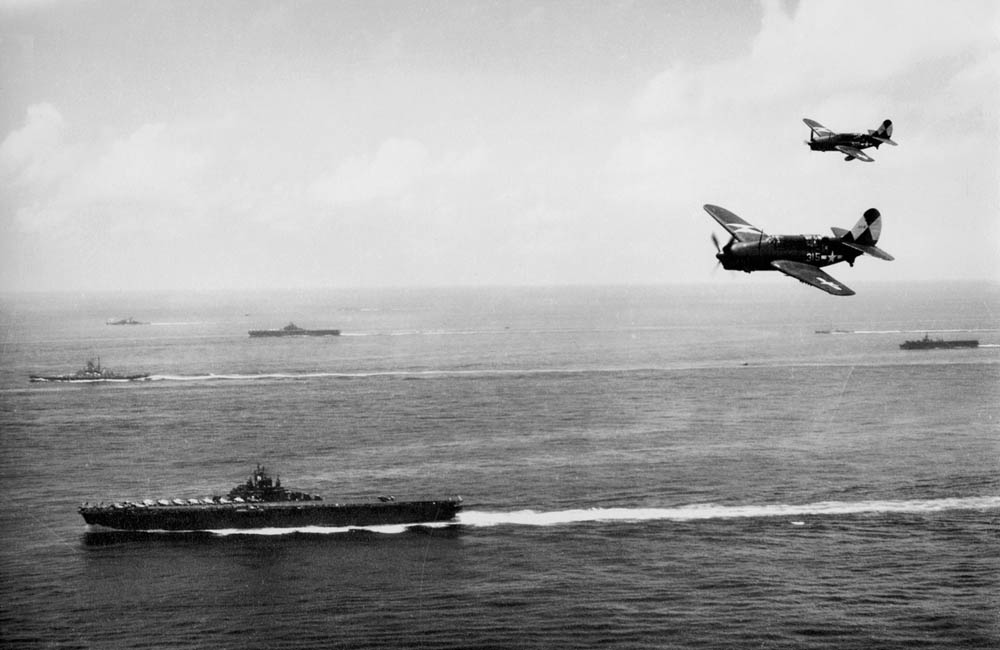 Curtiss SB2C-4 Helldiver dive bombers of Bombing Squadron 83 (VB-83) fly over the USS Essex (CV-9) off the coast of Okinawa, May 1945. (U.S. Navy Photograph.)