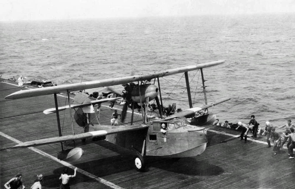 A British Supermarine Walrus flying boat lands the deck of an aircraft carrier in the Indian Ocean (Imperial War Museum Photograph.)