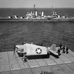 A Grumman F6F-3 Hellcat fighter is photographed on the aircraft carrier USS Yorktown as the U.S. Navy light cruiser USS Boise (CL-47) passes alongside. (U.S. Navy Photograph.)