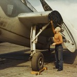 A plane caption inspects the landing gear of a Grumman TBF Avenger on the flight deck of a training escort carrier, circa 1943. (U.S. Navy Photo/National Archives.)