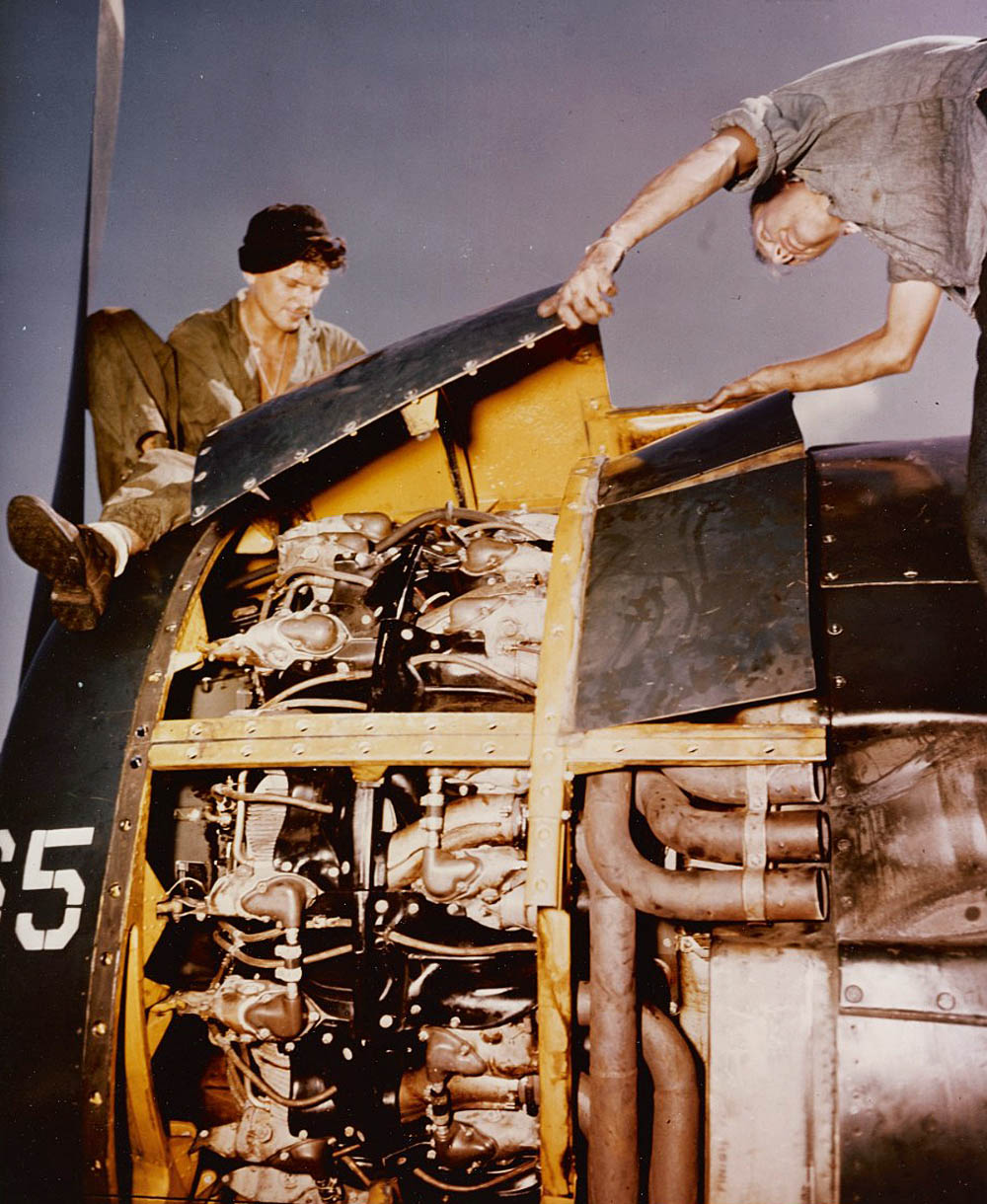 Sailors perform engine maintenance on a Grumman F6F Hellcat on the USS Yorktown somewhere in the Pacific. (U.S. Navy Photograph.)