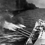 In August 1944, the USS Quincy (CA-71) Baltimore-class heavy cruiser fires her forward 8-inch guns at German positions. A smoke screen laid by another ship is visible in the background. (U.S. Navy Photograph, National Archives and Records Administration.)